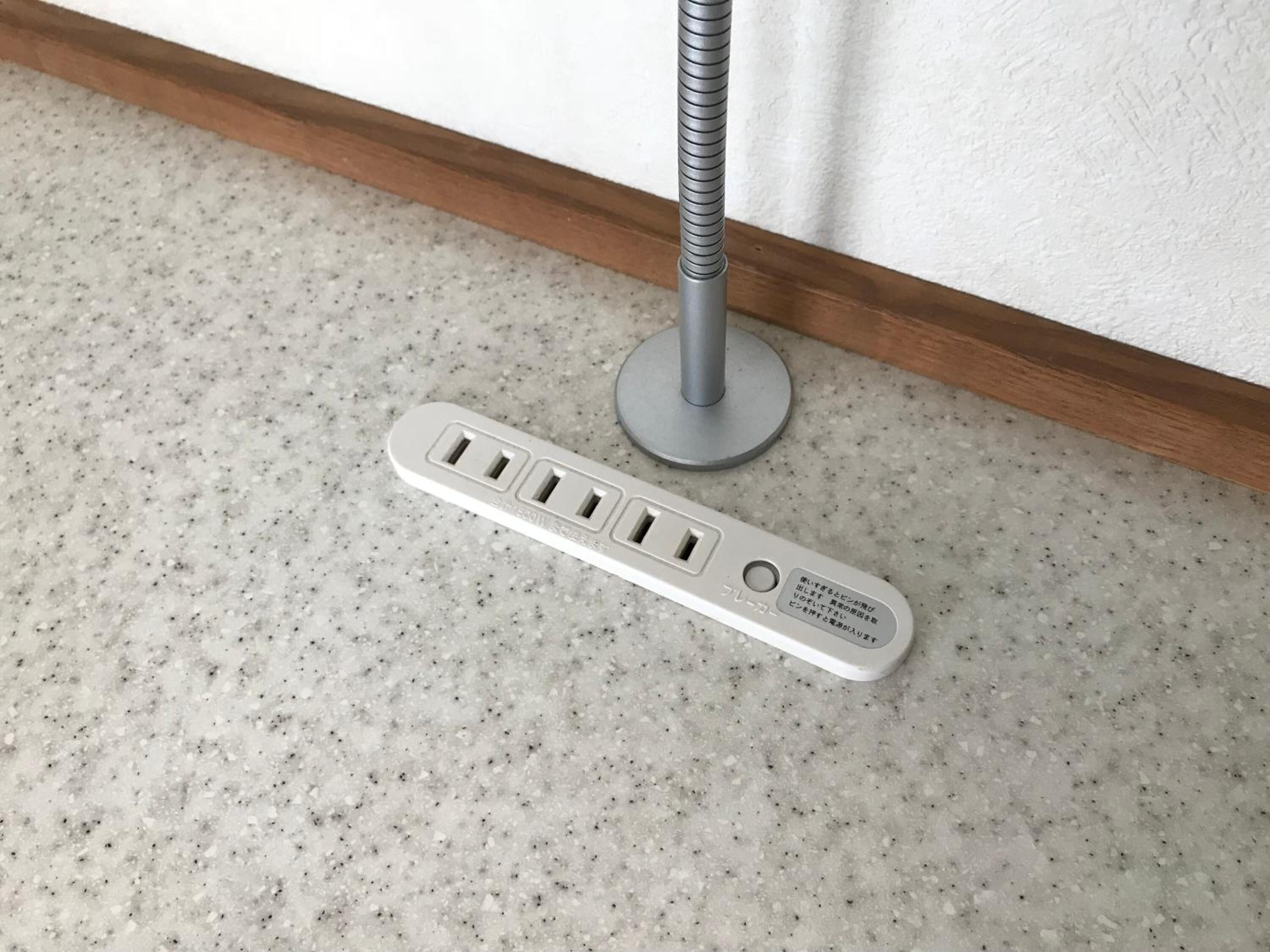A power strip with four outlets and a USB port on a speckled floor.