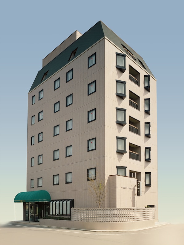 A modern hotel with a flat roof, multiple balconies, and a covered entrance.