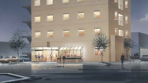 Ett hotell med flera våningar och modern design, med en framträdande entré med glasdörrar och ett väl synligt utomhusområde med sittplatser.