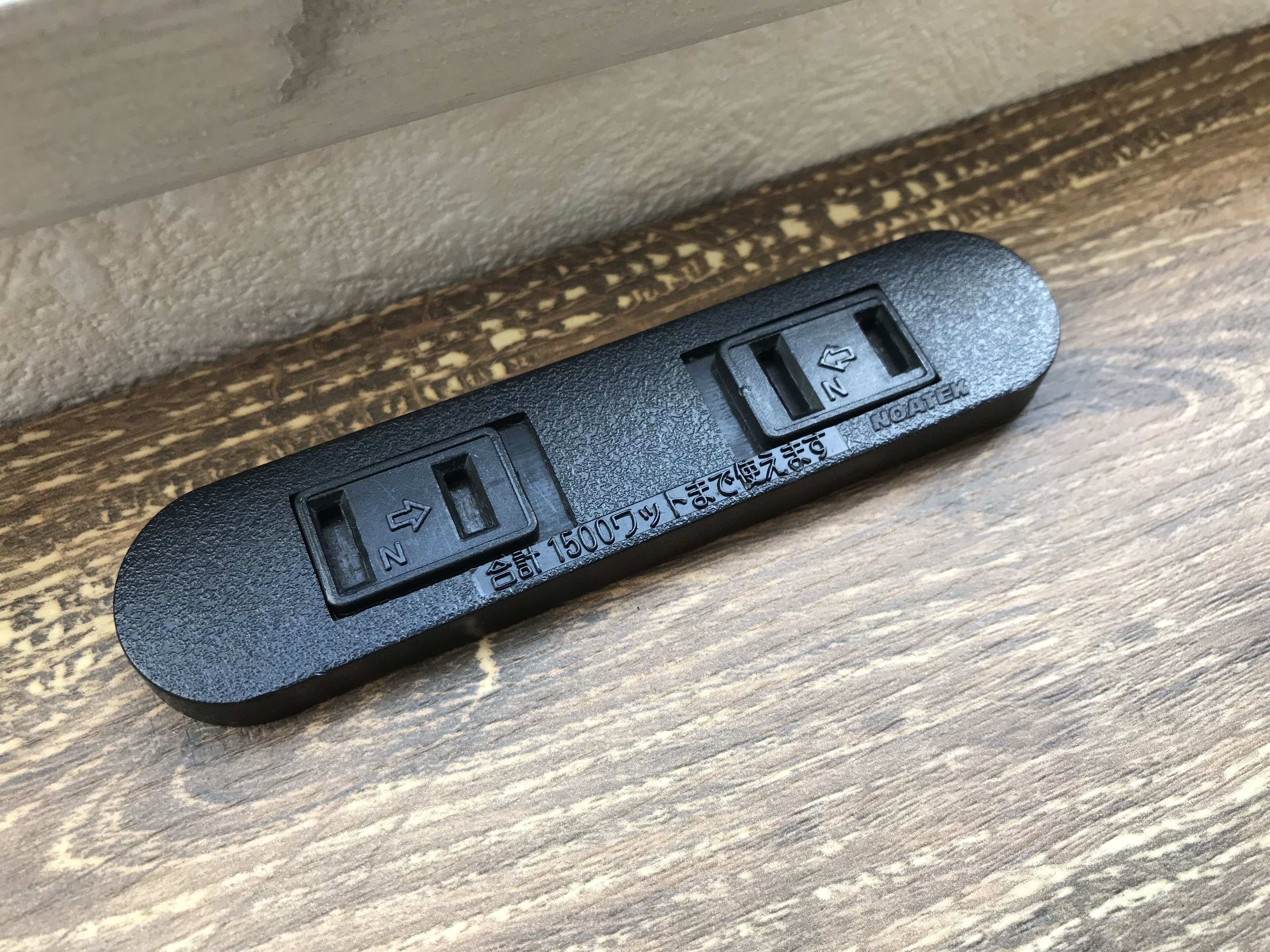 Eine schwarze Mehrfachsteckdose mit zwei Steckdosen und japanischem Text.