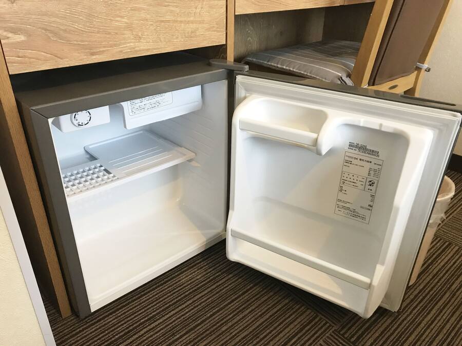 A compact refrigerator with a control panel, a small shelf, and a freezer compartment.