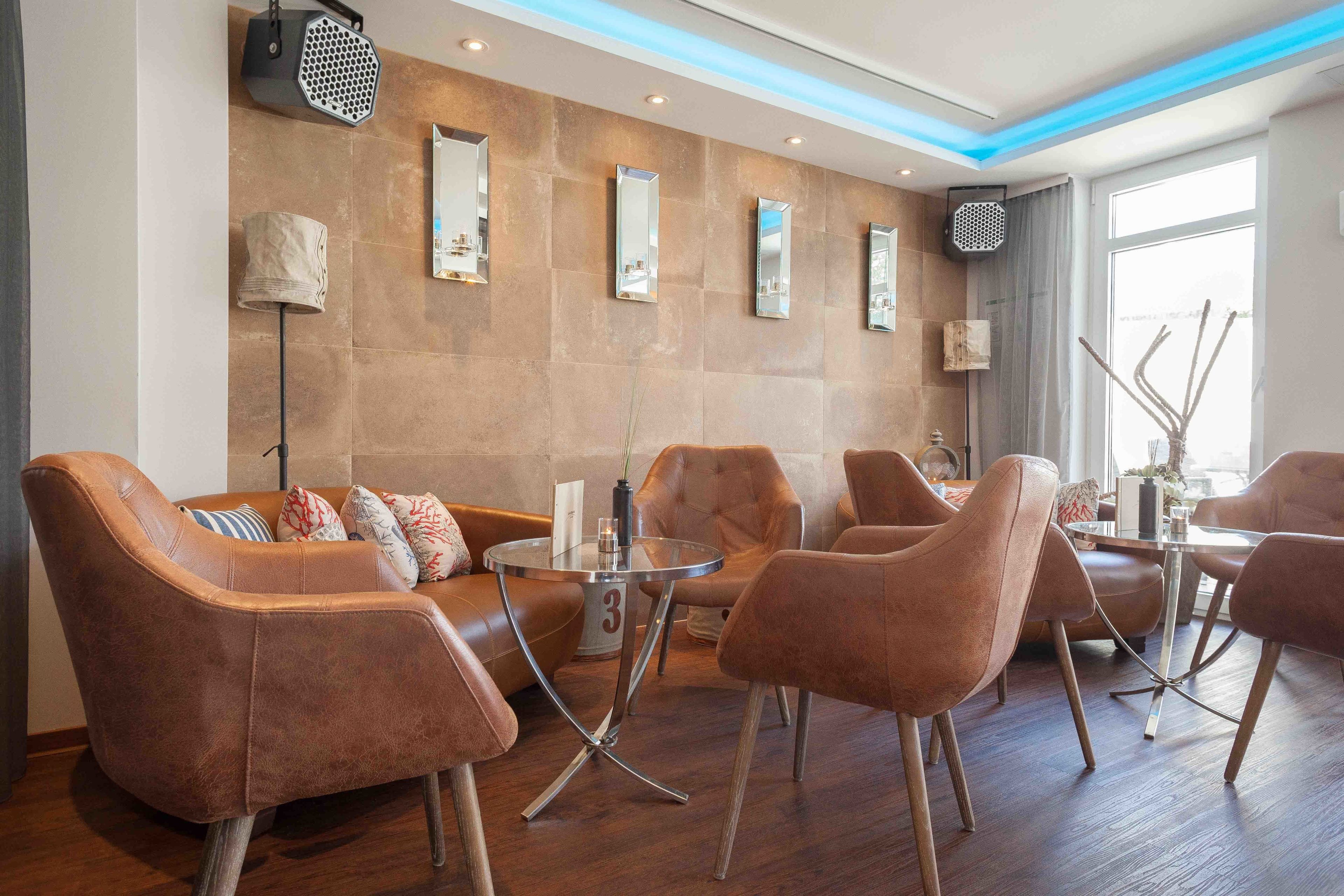 Un área de descanso moderna con sillones de cuero, una mesa de centro de vidrio y un espejo colgado en la pared.