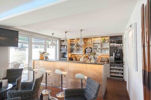 Una cocina moderna con barra, sillas de mimbre y diferentes electrodomésticos.