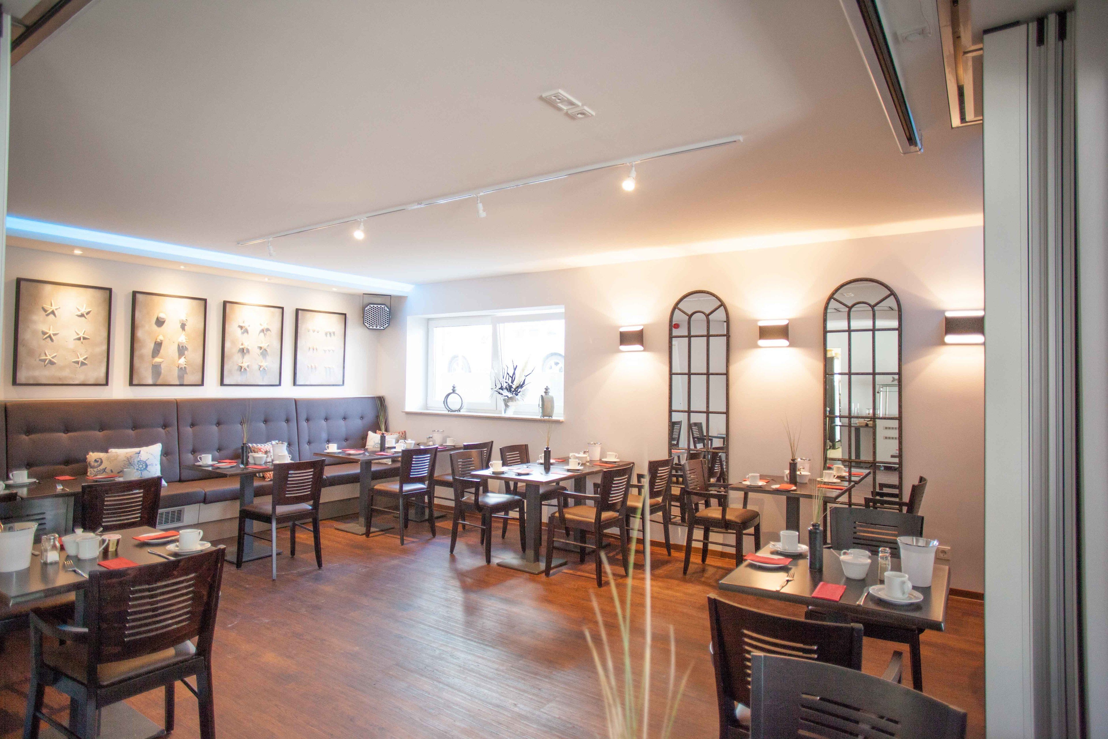 Ein Restaurant mit einer langen Theke, mehreren Tischen und einer gemütlichen Sitzgelegenheit mit einer Couch.
