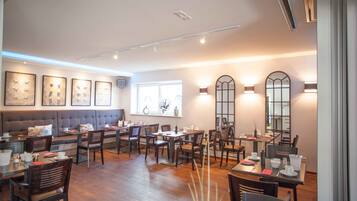 Ein Restaurant mit einer langen Theke, mehreren Tischen und einer gemütlichen Sitzgelegenheit mit einer Couch.