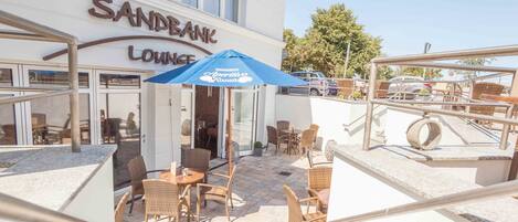 A Sandbank Lounge with outdoor seating and a blue umbrella.