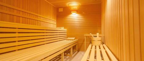Una sauna con bancos de madera y un asiento con un cubo.