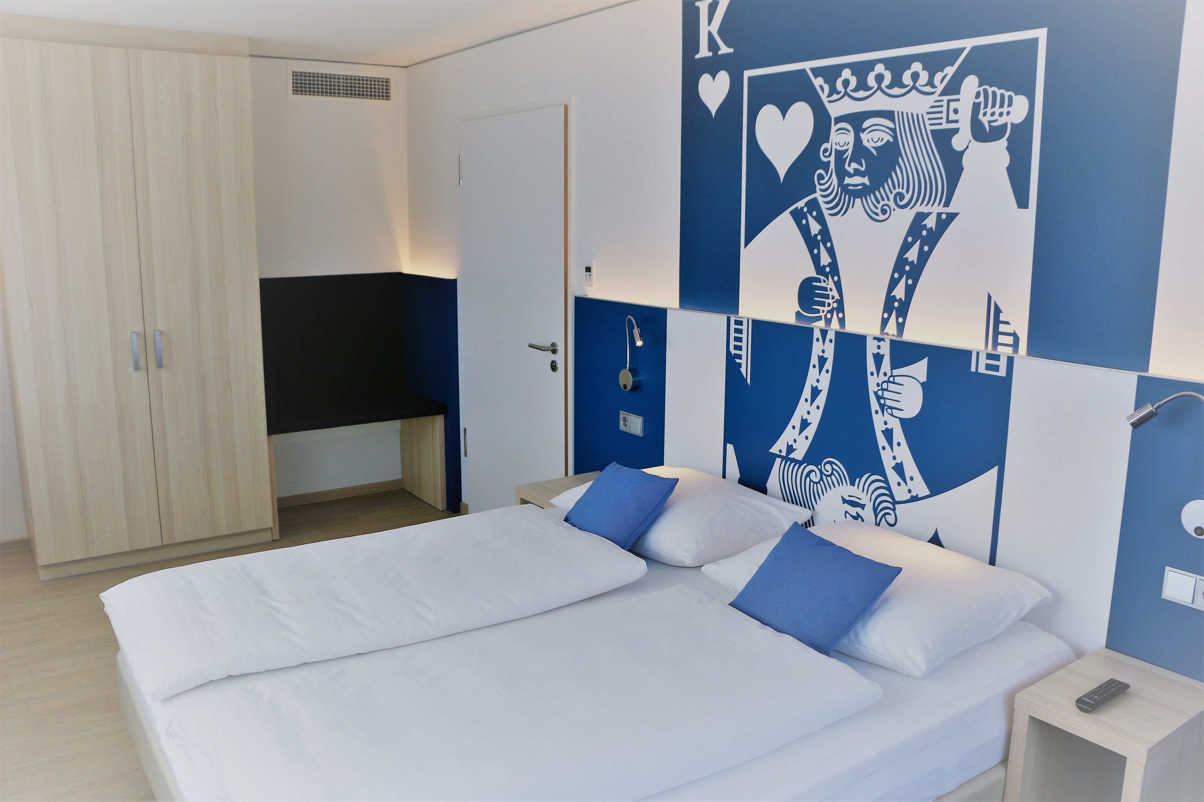 Habitación de hotel con cama, armario y pared con un diseño decorativo grande.