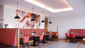 A modern restaurant with striped booths and tables, pendant lighting, and a large abstract painting on the wall. - Aparthotel Paderborn (Paderborn)