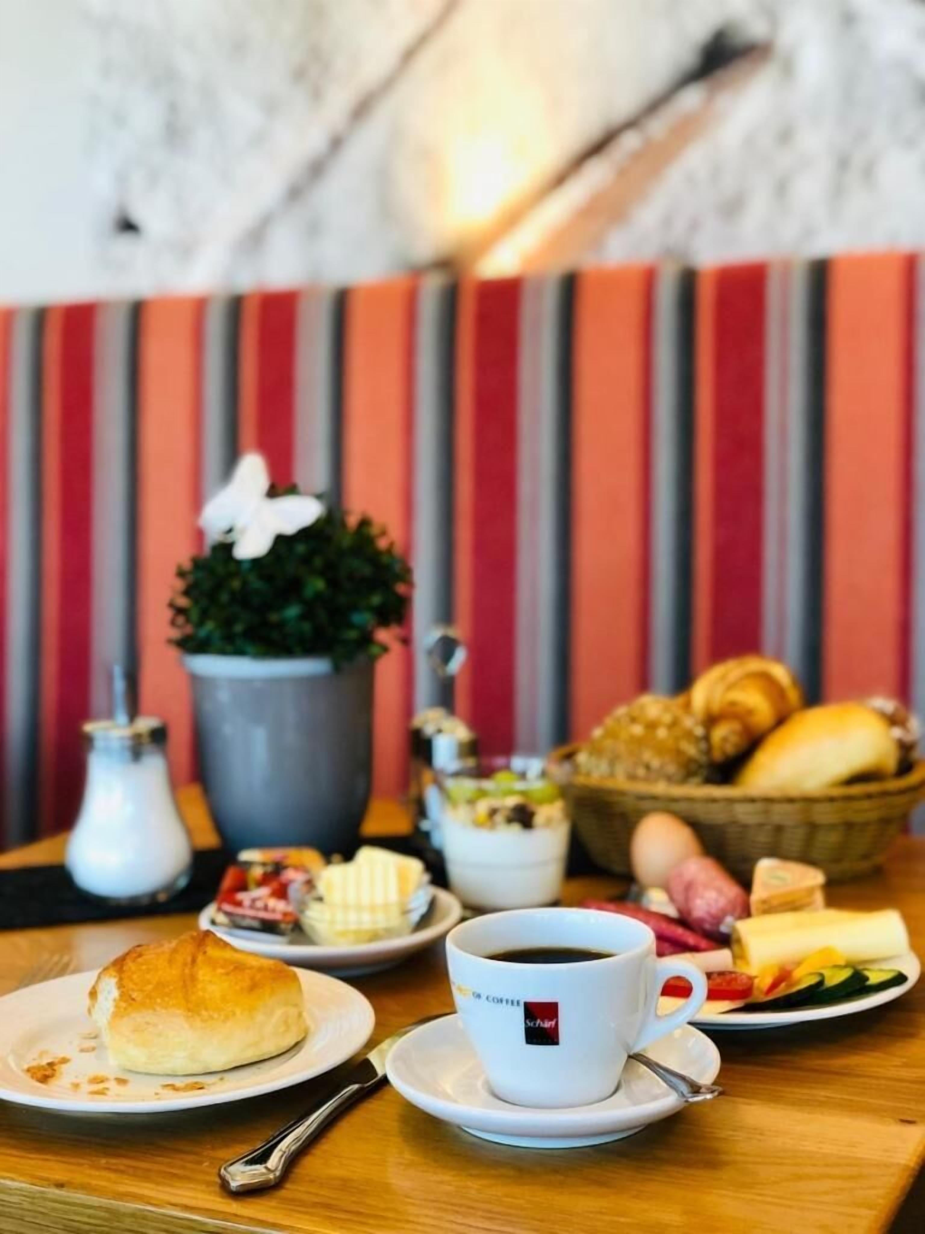 Ein Tisch mit einer Kaffeetasse, einem Gebäck und einem Teller Essen.