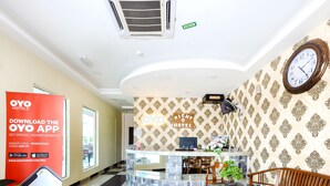 A hotel reception area with a modern design, including a reception desk, seating area, and a clock on the wall. - Night Queen Hotel (Sepang)