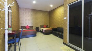 A hotel room with a bed, a desk with a chair, a sofa, and a sliding glass door. - Night Queen Hotel (Sepang)