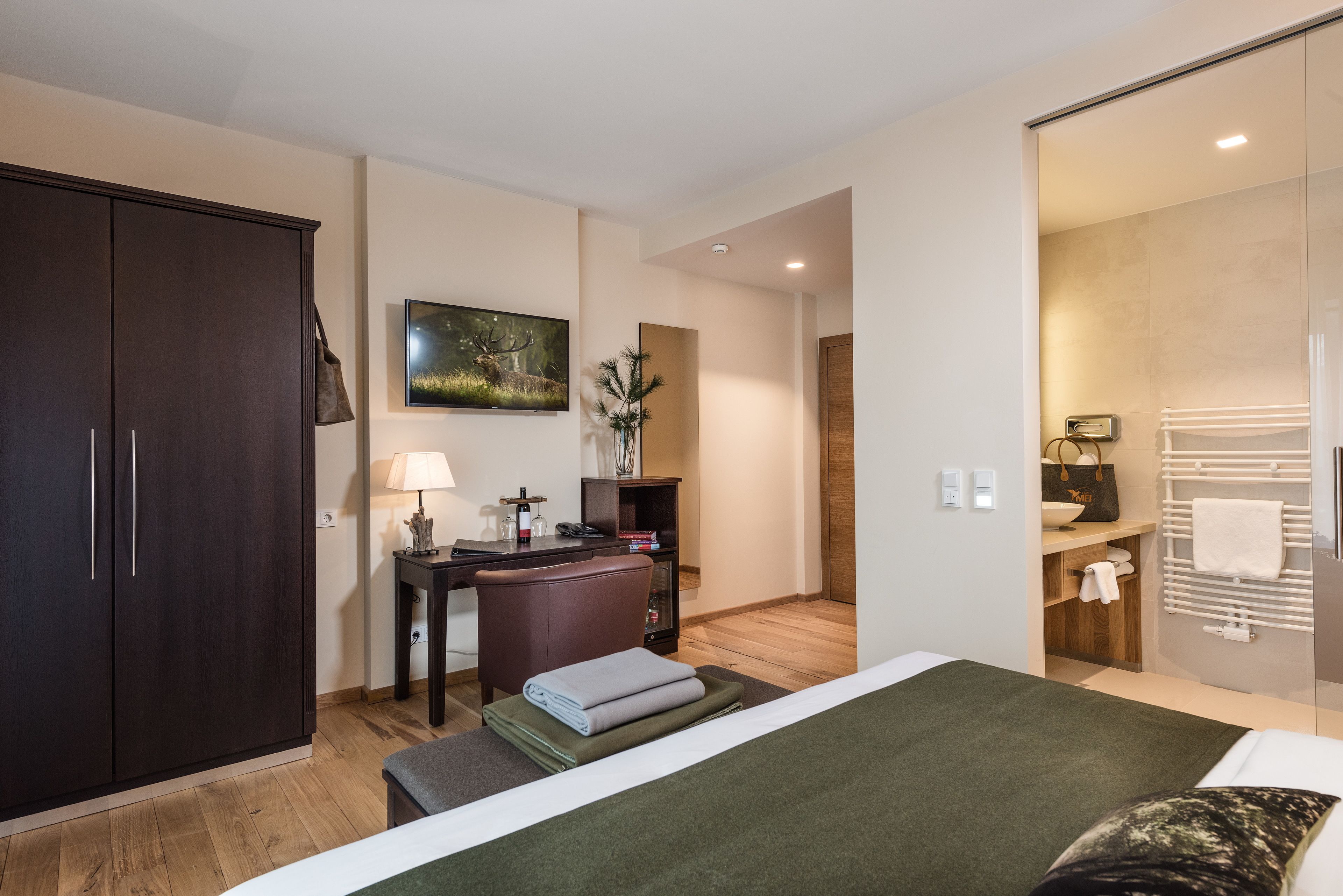 A hotel room with a bed, a desk, a wardrobe, and a bathroom.