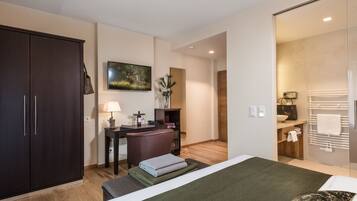 A hotel room with a bed, a desk, a wardrobe, and a bathroom.