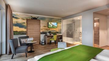 Una habitación de hotel con cama, escritorio, silla, televisor y baño.