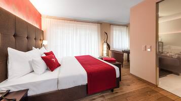 A hotel room with a large bed, a desk, and a wardrobe.