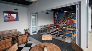 A modern dining area with wooden furniture, a checkered floor, and a colorful mural on the wall. - Umah Bali Suite and Residence (Denpasar)