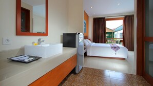 A hotel room with a bathroom, a bed, a TV, and a view of the outside. - Umah Bali Suite and Residence (Denpasar)