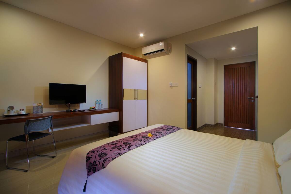 Une chambre d’hôtel équipée d’un lit, d’un bureau avec une chaise, d’une télévision et d’un appareil de climatisation.