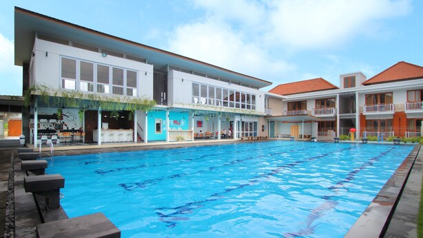 A swimming pool with lounge chairs and a restaurant named "KITE ENGLAND" adjacent to it. - Umah Bali Suite and Residence (Denpasar)