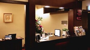 Una mesa de recepción con una computadora, una planta y un cuadro en la pared.