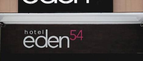 A hotel sign with the name 'hotel eden 54' in white and pink letters on a black background.