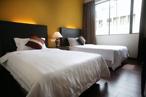 A hotel room with two beds, a nightstand with a lamp, and a window with curtains. - Hotel Eden54 (Kota Kinabalu)