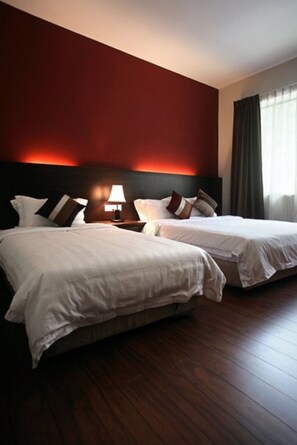 A hotel room with two beds, a nightstand with a lamp, and a red accent wall. - Hotel Eden54 (Kota Kinabalu)