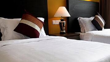 Una habitación de hotel con dos camas, una mesita de noche con una lámpara y un cabecero grande y oscuro.