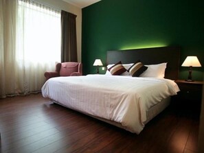 A hotel room with a large bed, two bedside lamps, a chair, and a green wall. - Hotel Eden54 (Kota Kinabalu)