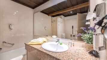 A bathroom with a granite countertop, a white sink, a mirror, a towel rack, and a potted plant.