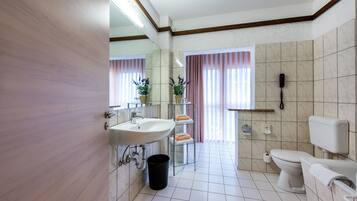 A modern bathroom with a sink, mirror, toilet, and a telephone.