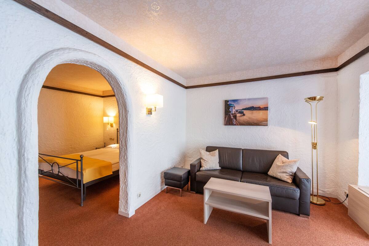 Una habitación con cama, sofá, mesa de centro y un cuadro en la pared.