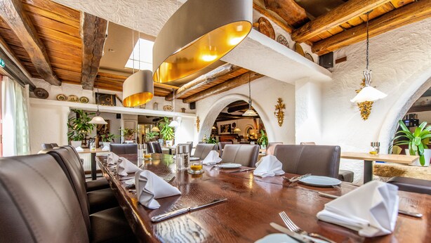 Un comedor con una mesa de madera dispuesta para una comida, rodeado de sillas.