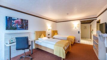 A hotel room with two beds, a desk with a chair, a painting on the wall, and a TV on the right.