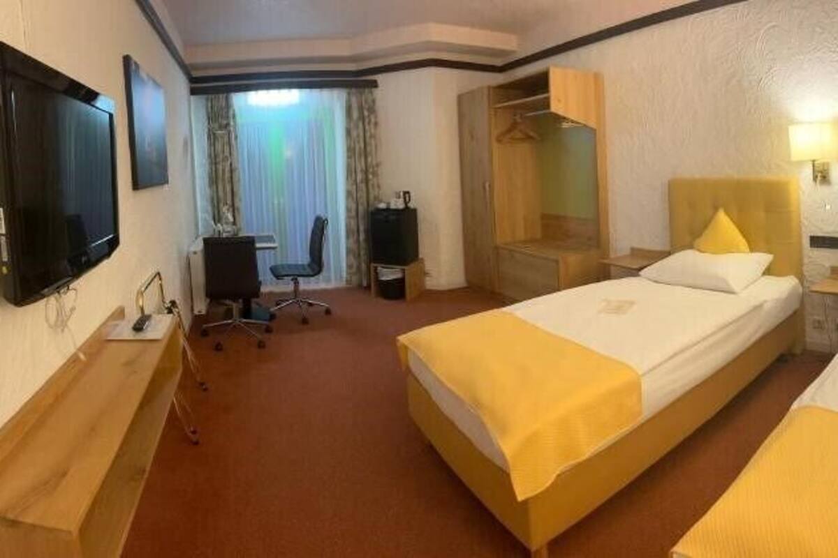 Una habitación de hotel con dos camas, un escritorio, una silla, un televisor y un espejo.