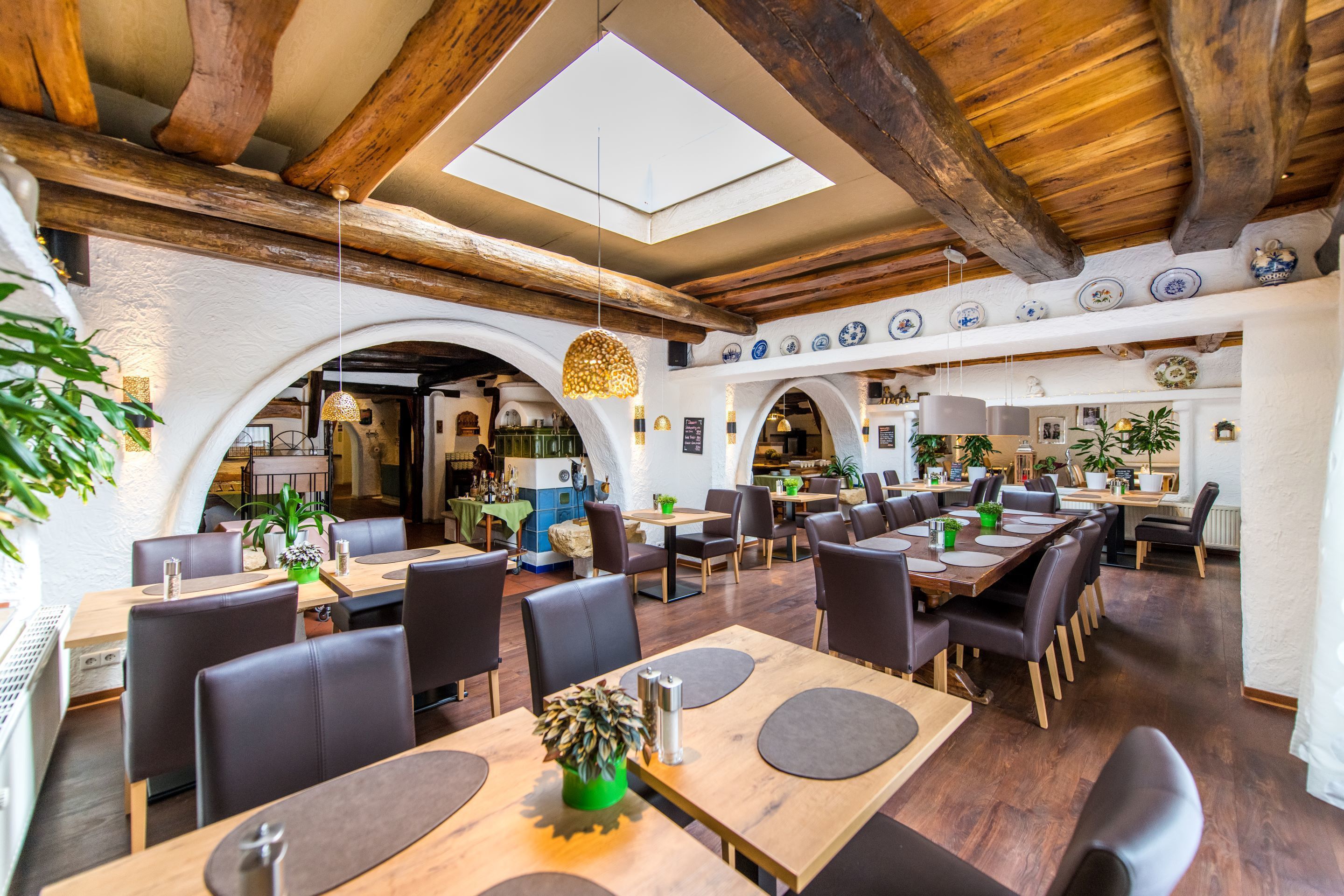 A restaurant with wooden beams, a skylight, and a variety of seating arrangements.
