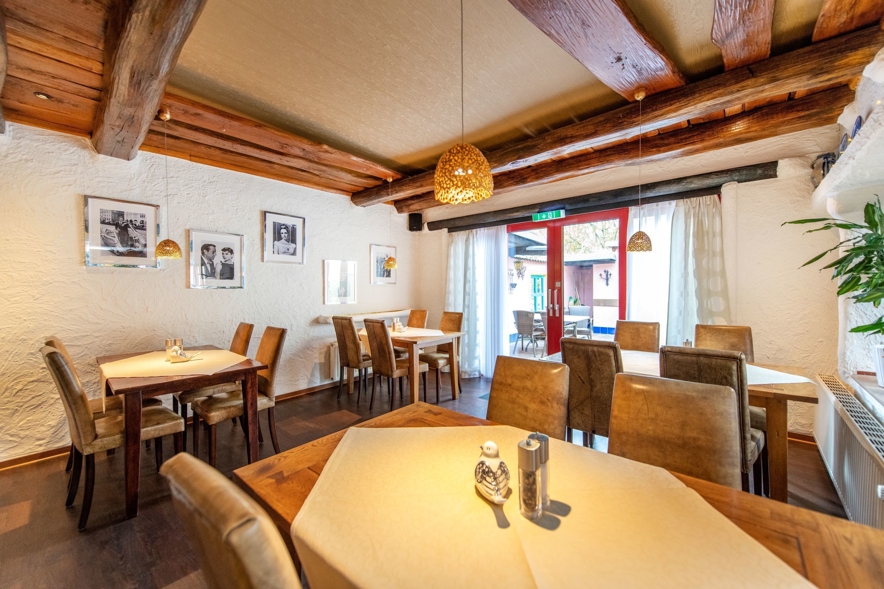 Ein Essbereich mit Holztischen und -stühlen, gerahmten Bildern an den Wänden und einer hängenden Leuchte.