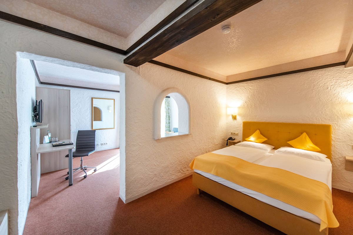 Una habitación de hotel con una cama, un escritorio y una silla.