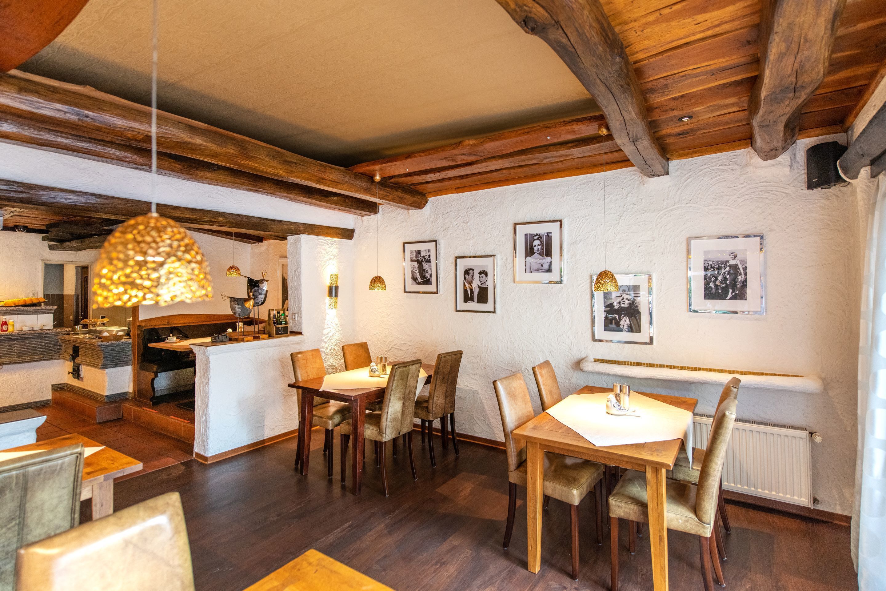 A restaurant with wooden beams, a bar area, and framed photographs on the walls.