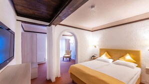 Una habitación de hotel con una cama grande, un televisor y un techo de madera.
