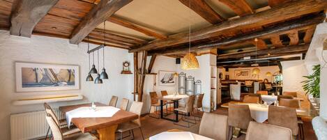 Un restaurante con vigas de madera, paredes blancas y una variedad de mesas dispuestas.