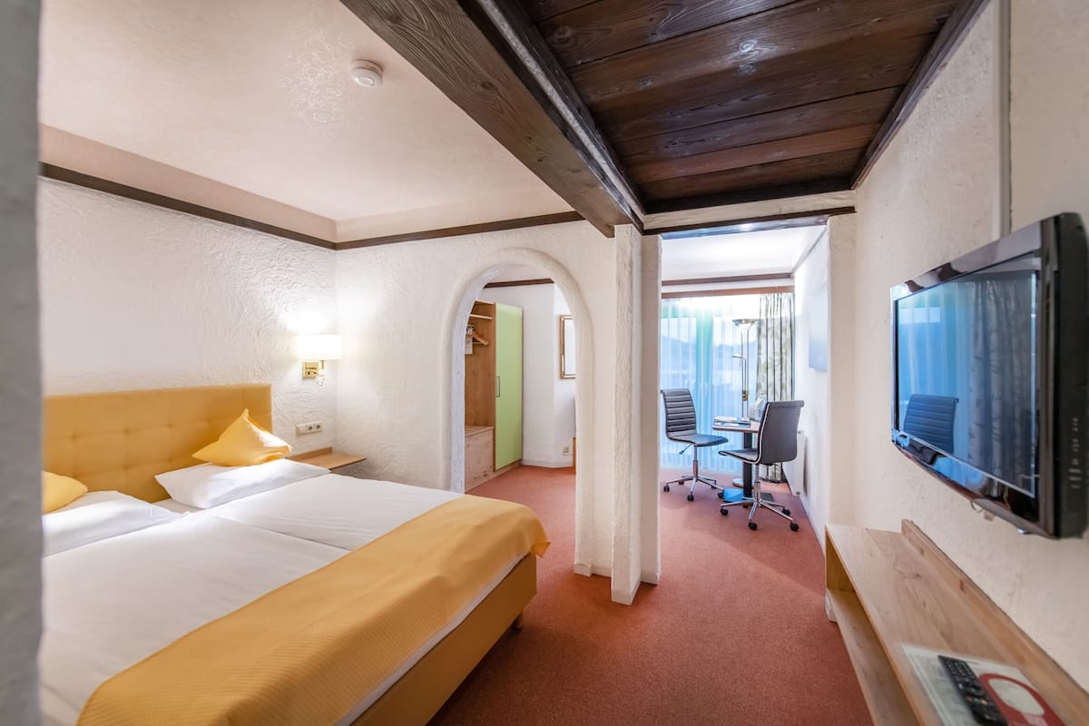 Una habitación de hotel con cama, televisión y escritorio con silla.
