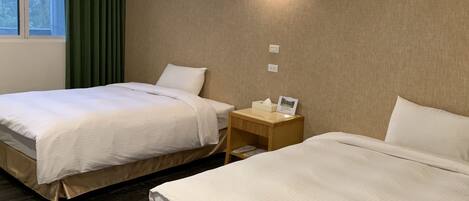 A hotel room with two beds, a nightstand with a lamp, and a window with curtains.