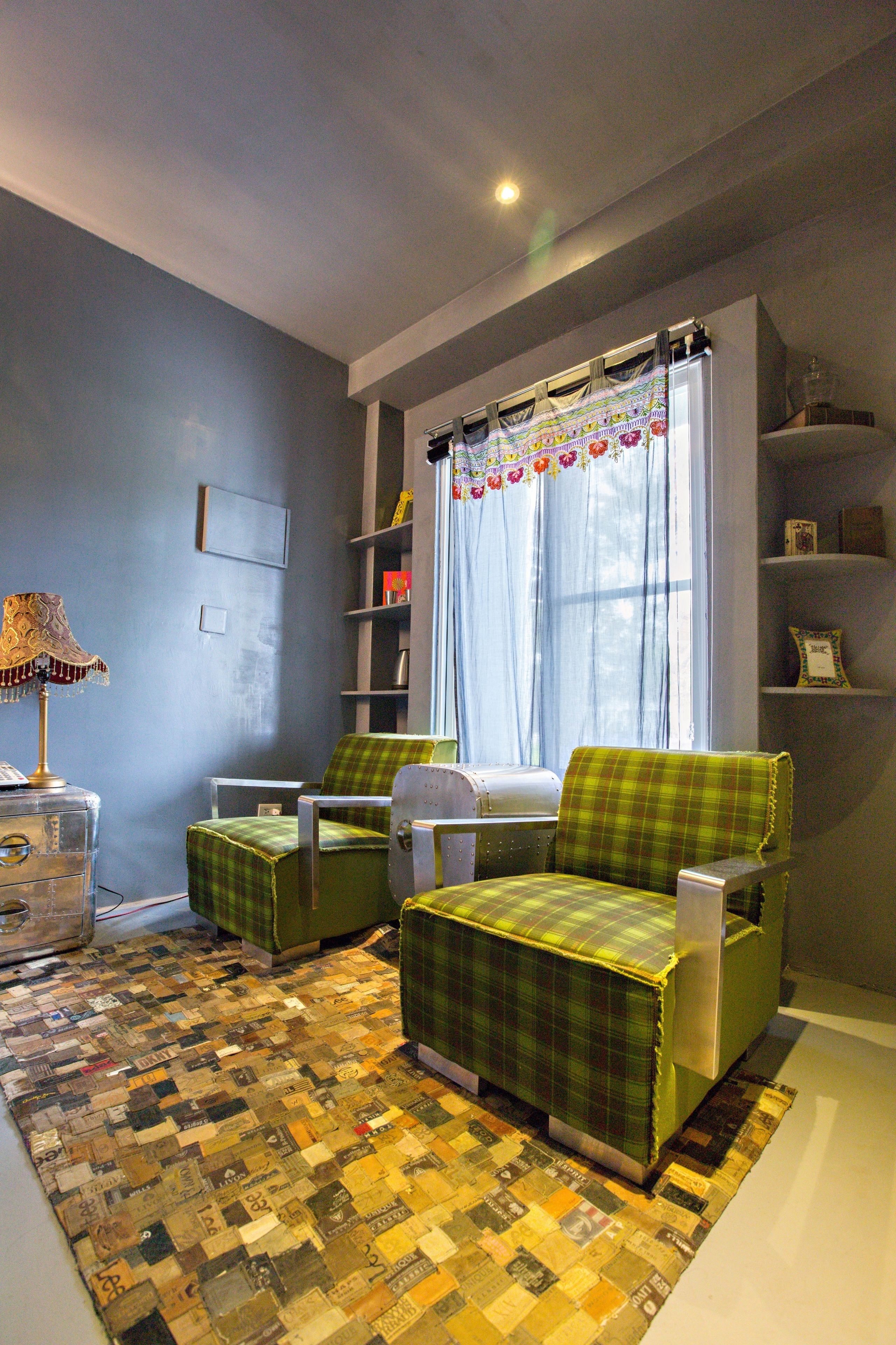 A room with a checkered floor, green armchairs, a lamp, and a window with curtains.