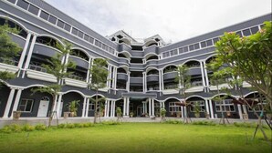 A multi-story building with a central courtyard, surrounded by balconies and potted plants.