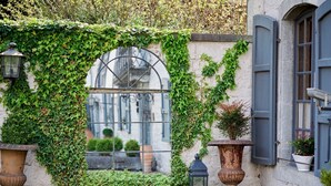 A narrow alley with a window covered in ivy, flanked by two large urns and a lantern. - Hotel la Malle Poste (Rochefort)