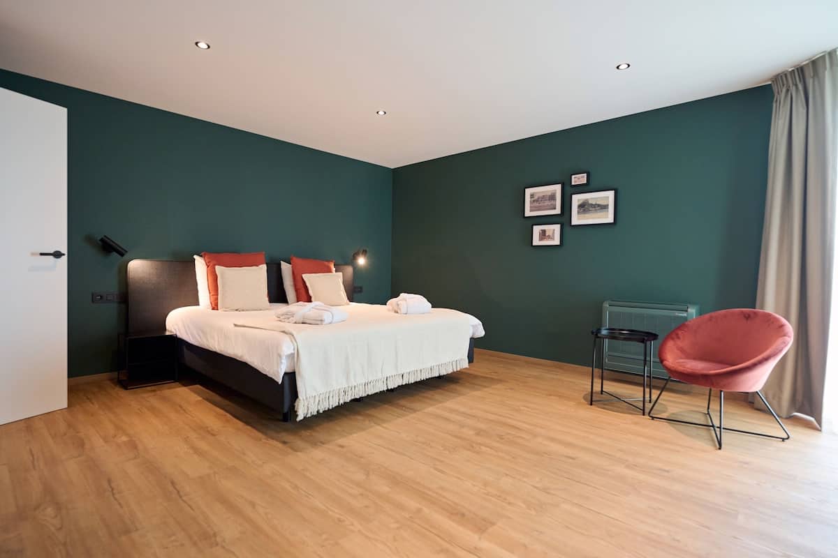 A modern bedroom with a bed, a chair, and a wall-mounted heater.