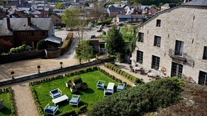 A courtyard with outdoor seating, a stone building, and a view of a residential area. - Hotel la Malle Poste (Rochefort)