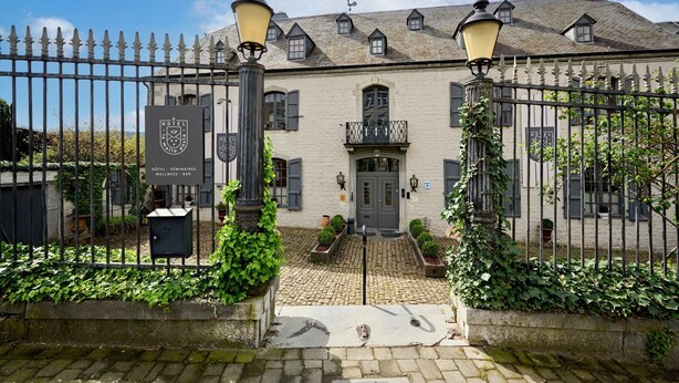 A historic building with a gated entrance, a cobblestone pathway, and a well-maintained garden. - Hotel la Malle Poste (Rochefort)